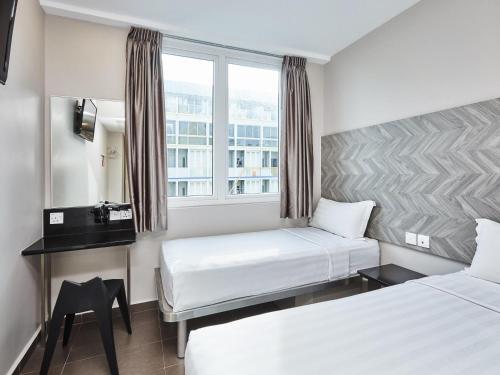 a hotel room with two beds and a window at ibis budget Singapore Ruby in Singapore