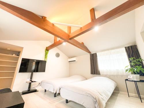 a bedroom with two beds and a flat screen tv at Rino-Haku 02 in Anan