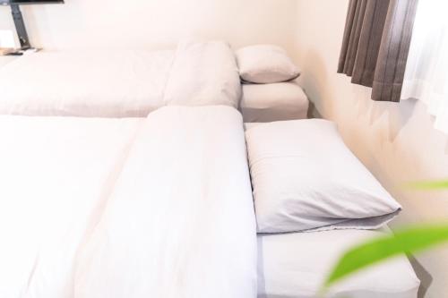 two beds in a room with white sheets and pillows at Rino-Haku 02 in Anan