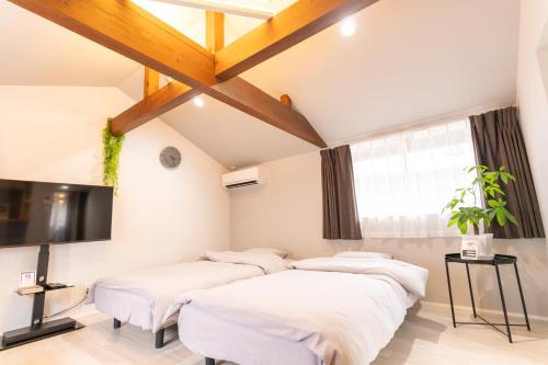 a room with four beds and a flat screen tv at Rino-Haku 02 in Anan