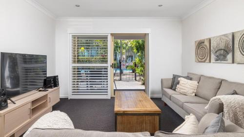 a living room with a couch and a tv at Oaks Pacific Blue Pool spa more in complex in Salamander Bay