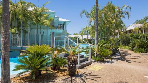 a house with a swimming pool and palm trees at Oaks Pacific Blue Pool spa more in complex in Salamander Bay
