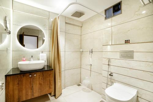a bathroom with a sink and a toilet and a mirror at Seaking Suites in Ernakulam