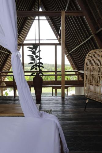 a bedroom with a bed and a large window at The Sawah Lodge, Seseh-Bali in Seseh
