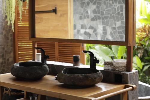 a bathroom with two black sinks on a wooden counter at The Sawah Lodge, Seseh-Bali in Seseh