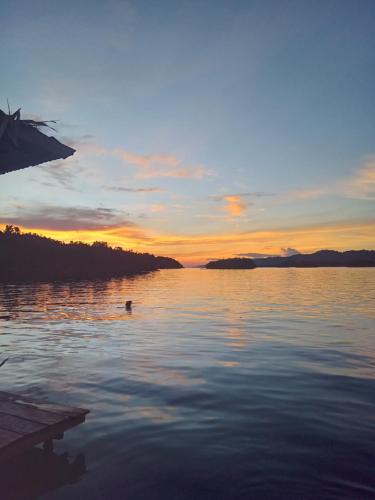 a person swimming in a lake at sunset at "Shady Sea Raja Ampat" in Besir