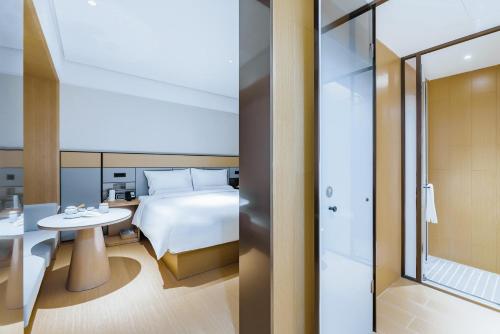 una habitación de hotel con una cama y una mesa en JI Hotel Shanghai Tonghe New Village Subway Station, en Baoshan