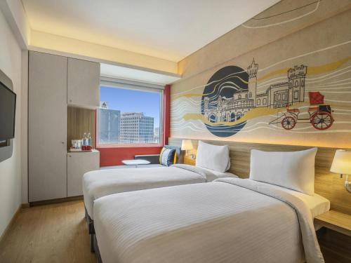 two beds in a hotel room with a painting on the wall at ibis Bengaluru Hebbal - An Accor Brand in Bangalore