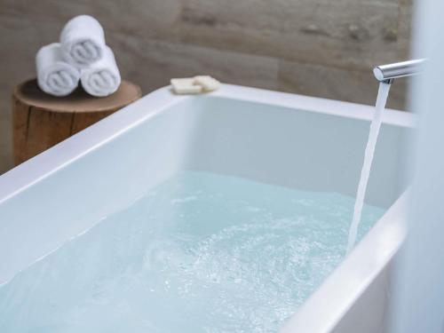 a bath tub filled with water and two rolls of towels at The Paragon Hotel Mexico Santa Fe By Accor in Mexico City