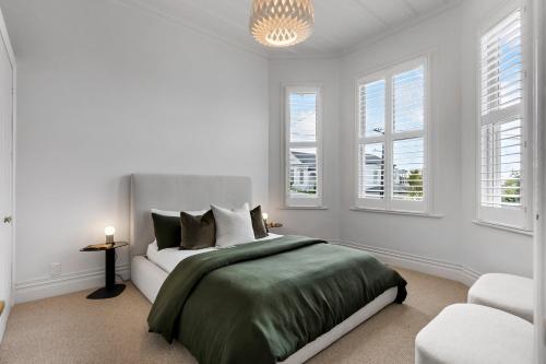 a white bedroom with a bed and two windows at Luxury Ponsonby Villa in Auckland