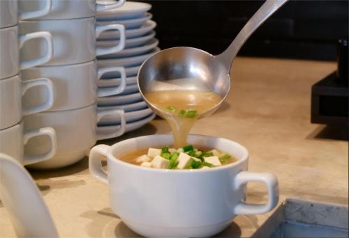 une cuillère verse de la soupe dans une tasse dans l'établissement ibis Styles Bangkok Sukhumvit Phra Khanong, à Bangkok