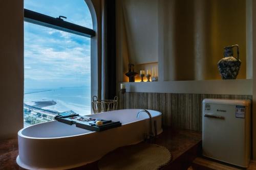 a bath tub in a bathroom with a large window at Shanheli Mediterranean Seaside Resort Homestay East Coast Branch in Ma Yu