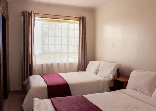 Stylish 3-BR Apt in Chuna, Kitengela في Athi River: غرفة فندق بها سريران ونافذة