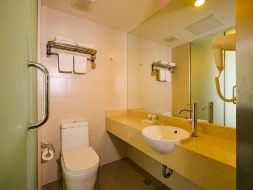a bathroom with a sink and a toilet and a mirror at Jinjiang Inn Style Shenyang The Palace Huaiyuan Gate in Shenyang