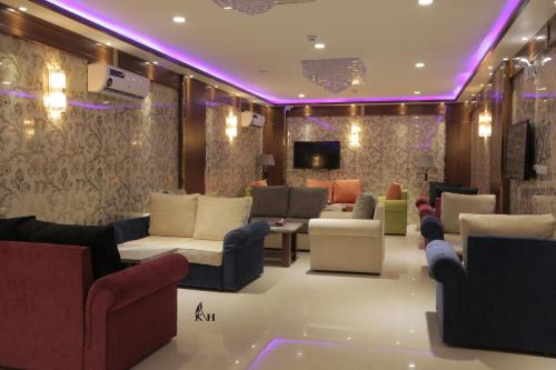 a living room with couches and chairs and a tv at Kadi Hotel in Najran