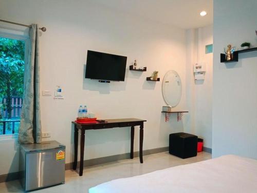 a bedroom with a desk and a television on a wall at Baan Bhuriwat Kiriwong in Khiriwong