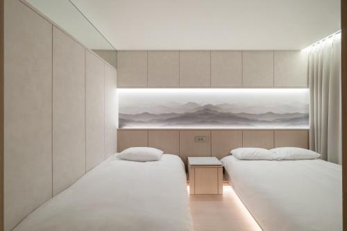 two beds in a room with white walls at 에스티르 신사 호텔 Estir sinsa hotel in Seoul
