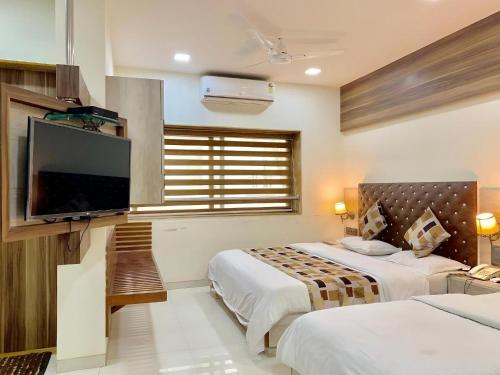 une chambre avec deux lits et une télévision à écran plat dans l'établissement Royale Heritage, à Nashik