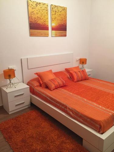 ブラナスにあるApartamento Puerto Blanesのベッドルーム1室(大型ベッド1台、オレンジ色の枕付)