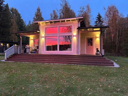 a small pink house with a large window and stairs at Log cabin by the lake in Pieksamaki