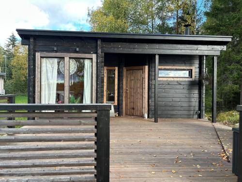 a small cabin with a wooden porch and a door at Log cabin by the lake in Pieksamaki