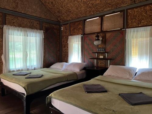 2 camas en una habitación con ventanas en PraiwanRaftHouse แพไพรวัลย์, en Ban Wang Khon
