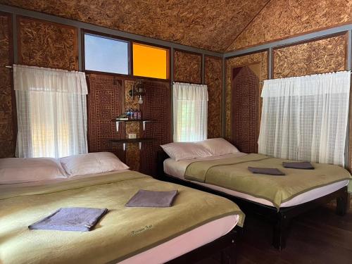 2 camas en una habitación con ventanas en PraiwanRaftHouse แพไพรวัลย์, en Ban Wang Khon