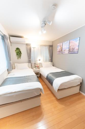 two beds in a bedroom with wooden floors at 4 卧室 - 3 浴室 - 3 卫生间 - 100 平方 新装 别墅 - 新宿 4 分钟 - Sakura House in Tokyo