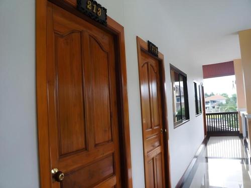 a wooden door with a clock on it next to a hallway at N-Joy Place in Surin