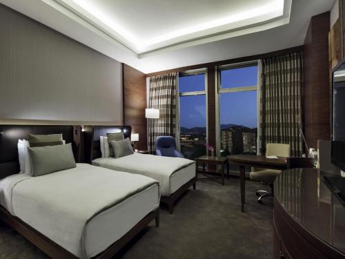 a hotel room with two beds and a desk at Movenpick Hotel Malatya in Malatya
