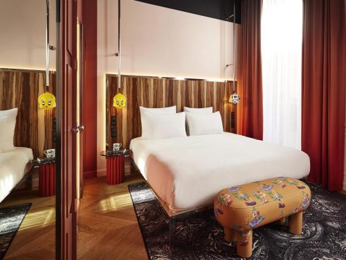 1 dormitorio con cama blanca grande y taburete en Mama Shelter Rennes, en Rennes