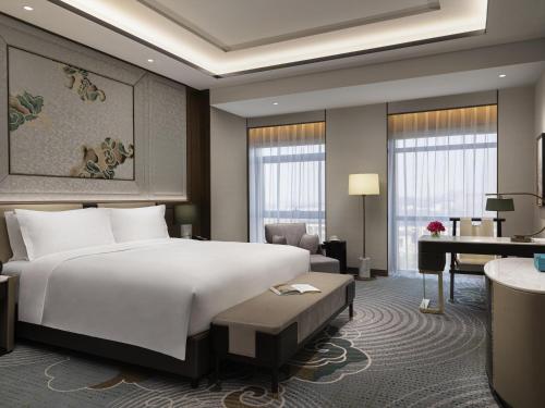 a hotel room with a large bed and a desk at Sofitel Xiong An in Baoding