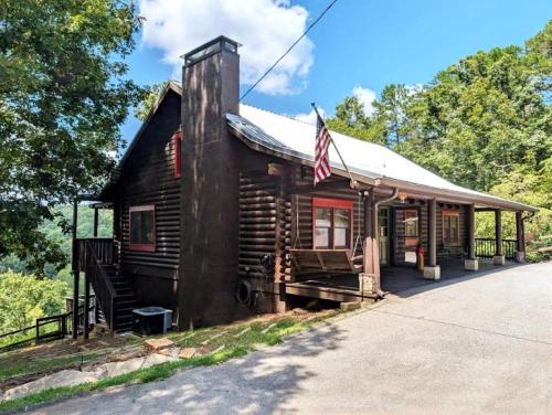DemorestにあるWooden Cabin with Hot-Tub and Pool Table in Demorest, Georgiaのアメリカ国旗が掲げられた古い丸太小屋