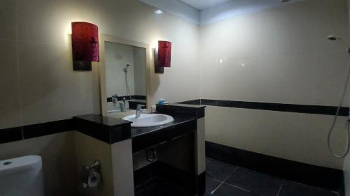 a bathroom with a sink and a toilet and a mirror at Nirmala Hotel & Convention Centre in Denpasar