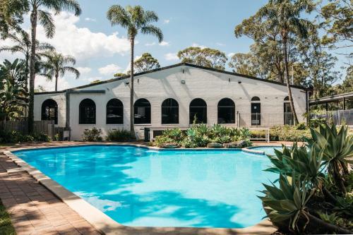 a church with a swimming pool in front of a building at Checkers Resort in Terrey Hills