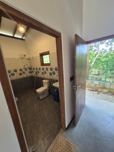 a bathroom with a toilet and a sink and a door at the cinnamon home in Koggala