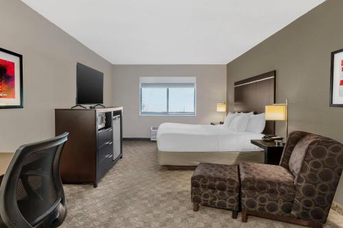 a hotel room with a bed and a chair at Comfort Inn Huntington near University area in Huntington