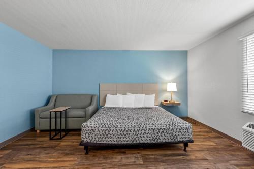 a bedroom with a bed and a chair in it at WoodSpring Suites St Peters-OFallon in Saint Peters