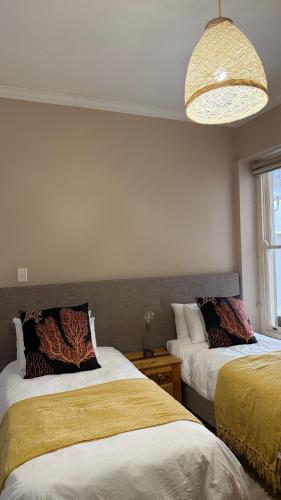 Un dormitorio con dos camas y una lámpara de araña. en Point View Selfcatering, en Mossel Bay