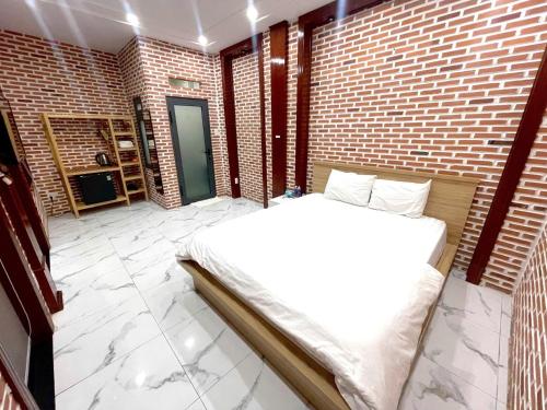 a bedroom with a bed and a brick wall at The Land Hotel & Apartment in Vung Tau