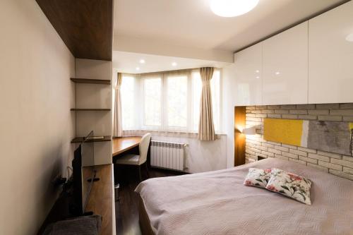 a bedroom with a bed and a desk and a window at Lozenets Apartment in Sofia