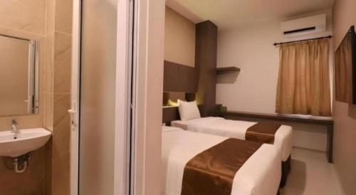 een hotelkamer met twee bedden en een wastafel bij NIVIA HOTEL in Pulauberayan Dadap
