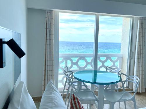 une table et des chaises dans une pièce avec vue sur l'océan dans l'établissement Beachside Apartments Cancun, à Cancún