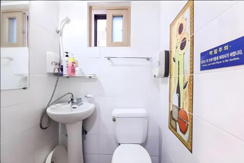 a white bathroom with a toilet and a sink at Ace Hotel in To-dong