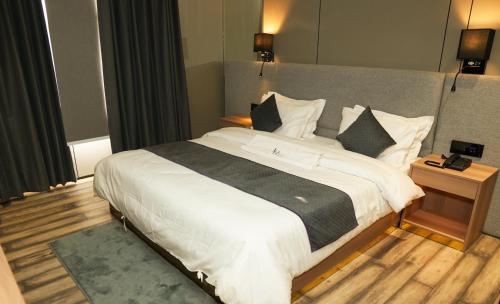 Un dormitorio con una cama grande con sábanas y almohadas blancas. en Hotel Aroma Inn, en Morādābād