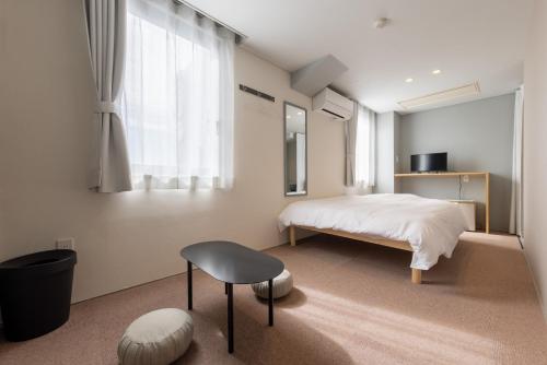 a bedroom with a bed and a chair and a window at Kanazawa 旅音 in Kanazawa