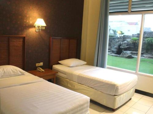 a hotel room with two beds and a window at Hotel Intan Cirebon in Cirebon