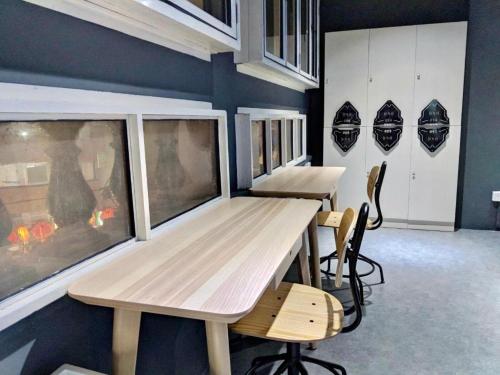 two tables and chairs in a room with helmets on the wall at MET A Space Pod @ Chinatown in Singapore