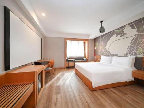 een hotelkamer met een bed, een bureau en een scherm bij Intercity Hotel Qingdao in Huangdao