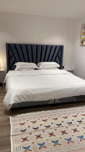 una cama con cabecero negro y una alfombra en شقة بغرفة وصالة, en Riad